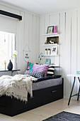 Black bed with drawers below in child's bedroom with board walls