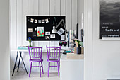 Purple spoke-back chairs and desk below pinboard on wall
