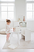 Little girl at play table in child's bedroom decorated entirely in white