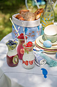Smoothies, Brotkorb und Geschirr fürs Osterfrühstück auf Tisch im Garten