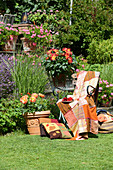Patchworkdecke in Orangetönen auf einem Stuhl im sonnigen Garten