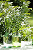 Fern fronds in glass bottles decorated with fern-shaped wooden pendants