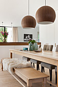 Wooden table with benches and globe lights in modern dining room
