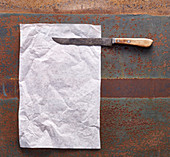 Backpapier und rostiges Messer auf Metalluntergrund