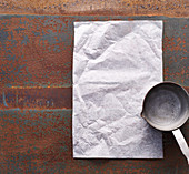 A saucepan and baking parchment on a rusty surface