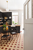 Kitchen in black and white with terracotta tiles and wooden table with flowers