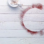 Dirty cake plates and cassis powder on a white wooden surface