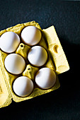 Weisse Hühnereier in gelbem Eierkarton