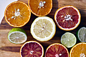 Various halved citrus fruits on a wooden cutting board