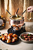 Cheese fondue with roast potatoes and sausages in bacon