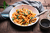 Vegan penne with lentil and carrot bolognese, wild garlic, sesame and yeast flakes