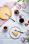 Kaffeetafel mit veganem Käsekuchen, frischen Früchten, Erdbeersauce, Kaffee und Tulpen