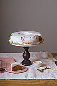 Vegan carrot cake with coconut cream frosting on wooden cake stand with one wedge cut and served on a plate