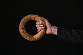 A Hand with a Bagel on a Black Background