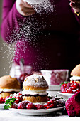 Kleine Victoria Sponge Cakes mit Marmelade, Sahne, Beeren und Puderzucker