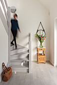 Hallway with curved wooden staircase and arranged flowers on small hall table