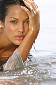 A young woman in the sea with her head in her hand