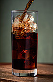 Iced coffee being poured into tall glass.