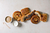 Variety of traditional french puff pastry buns with rasin and chocolate, croissant with paper cup of coffee and milk