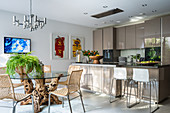 Dining table with burl wood base in front of beige, modern, open-plan kitchen