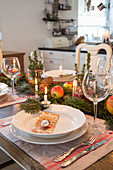 Weihnachtlich gedeckter Tisch mit Nadelzweigen und Äpfeln als Deko