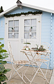 Vintage-style metal garden furniture outside pale blue summer house