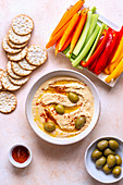 Red lentil hummus with sliced vegetables and crackers on the table
