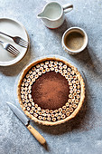Chocolate hazelnut tart on the table with a cup of coffee and cream