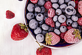 Plate with fresh and frozen various berries (bilberry, raspberry, blueberry, strawberry)