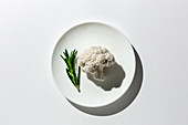 Raw cauliflower bouquet with rosemary from above with sunlight