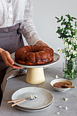 Anonymous female in apron putting plate with fresh Bundt cake