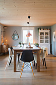 Various chairs around wooden table in dining room of modern country house