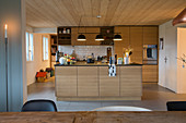 Blick in die beleuchtete, moderne Küche mit Holzfronten