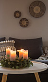 Advent wreath with lit candles in grey living room