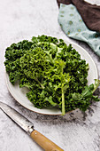 Plate with green leaves of ripe kale placed near knife
