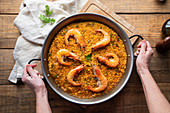 Paella with roasted shrimps against rustic table