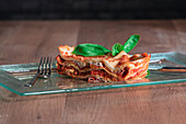 Delicious baked lasagna in glass dish on table