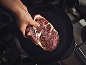 Placing a steak in a cast iron pan