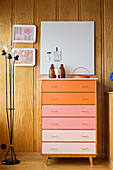 Chest of drawers with drawers in colour gradient against wood-panelled walls