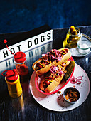 Hot Dogs auf dänische Art mit roten Zwiebeln, Röstzwiebeln und Essiggurke