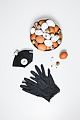 Various eggs in a bowl with a protective mask and black gloves