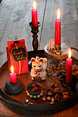 Festive arrangement with red candles and Maneki-neko cat on tray