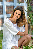 A young woman wearing a white blouse with lace panel and white shorts