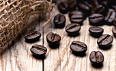Geröstete Kaffeebohnen auf Holzuntergrund (Nahaufnahme)