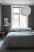 Paper lampshade above bed in white and grey bedroom