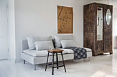 Stool used as coffee table in front of grey-striped sofa on white floor