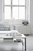 Coffee table and filing cabinets in living room decorated entirely in white