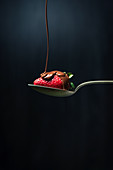 Chocolate being drizzled onto a strawberry on a spoon