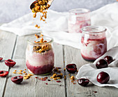 Yoghurt in pots with cherries, cherry sauce and granola