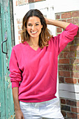 A young woman wearing a pink jumper and white trousers